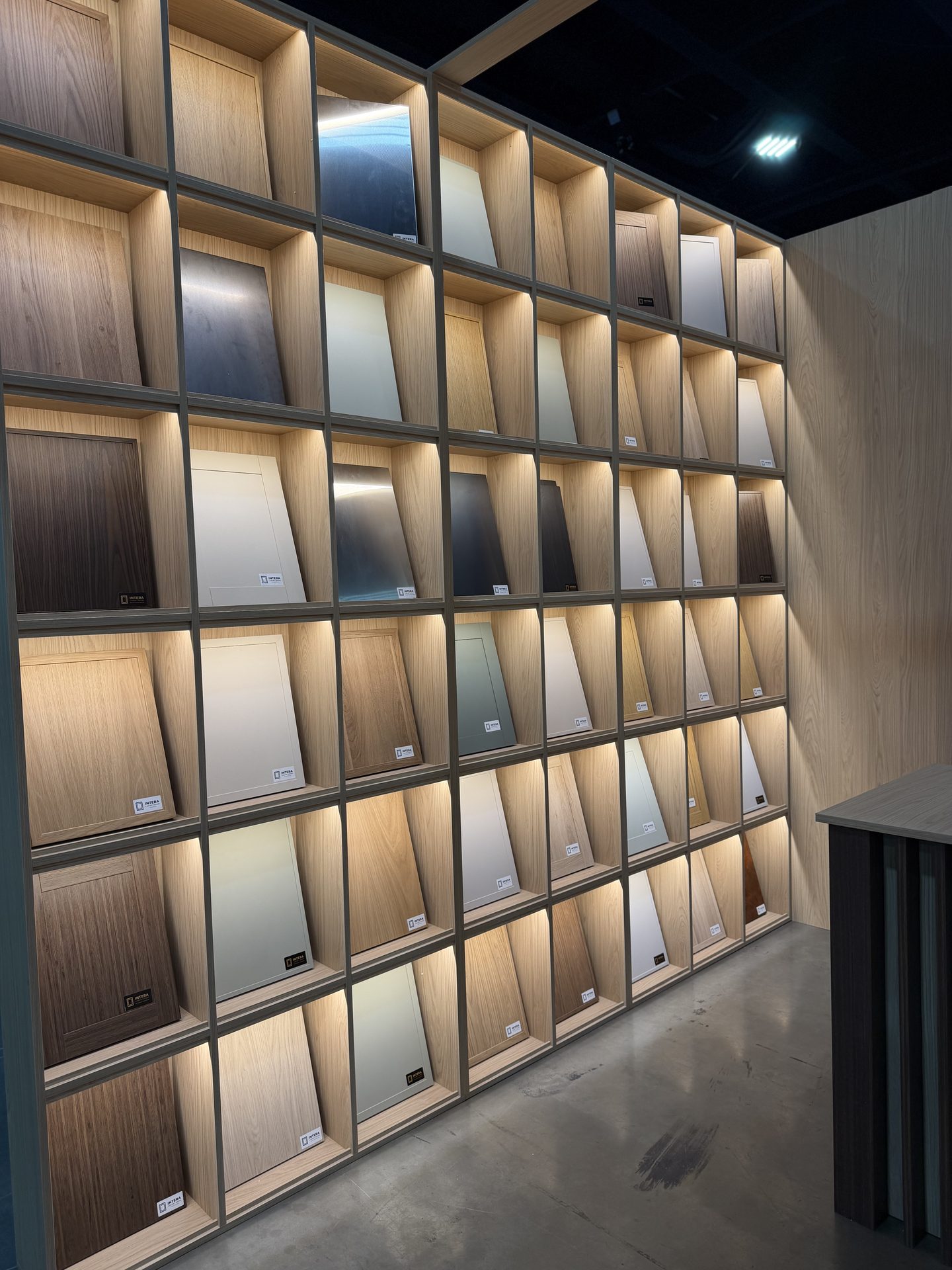The INTERA material wall: lit shelves of door samples in woodgrain and solid finishes